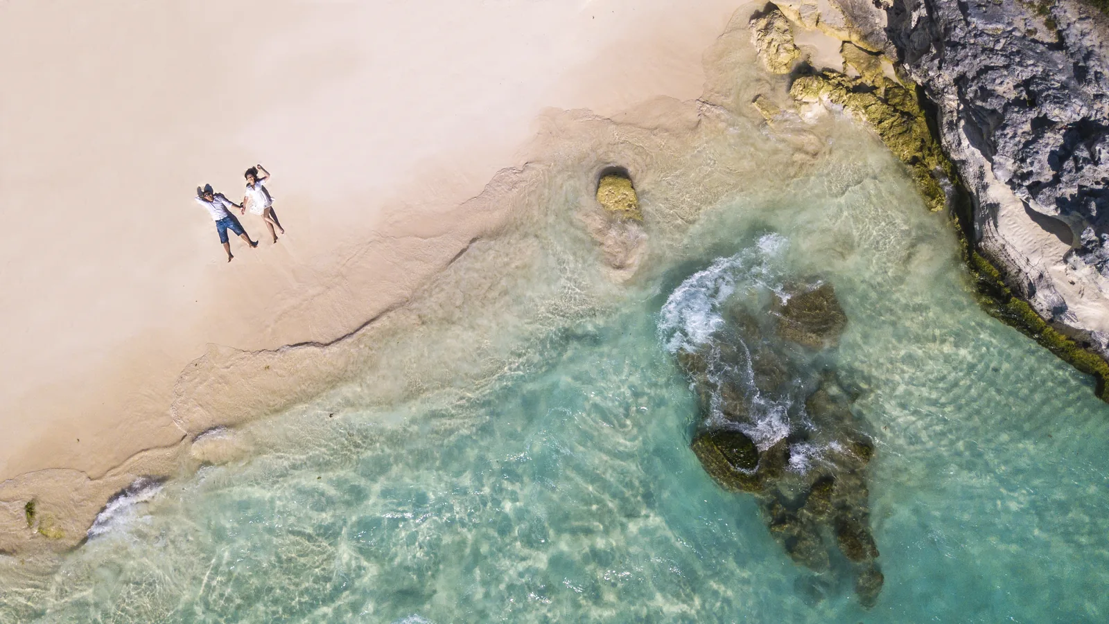 Aerial drone photograph of a couple on a beach, cinematic overhead wedding coverage